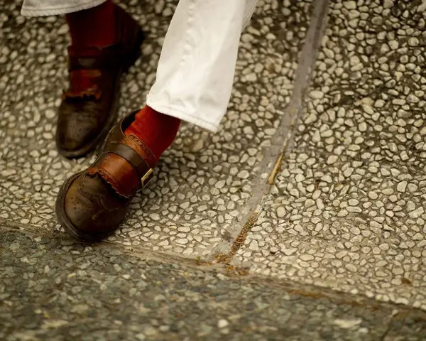 Scarpe marroni uomo con fibbia e calzini rossi, perfette per un look casual chic.