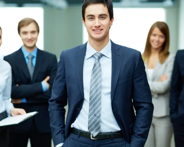 Equipo profesional sonriendo. Un ejemplo de como ir vestida a una entrevista de trabajo: traje oscuro, camisa clara y corbata.