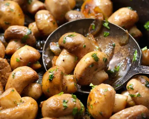 Champiñones salteados con perejil, perfectos para tus recetas con champiñones. Una cuchara sirve para probarlos.