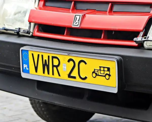 Czerwony grill z logo, reflektor i żółta tablica rejestracyjna z napisem VWR 2C oraz symbolem starego samochodu. To jest rejestracja dw.