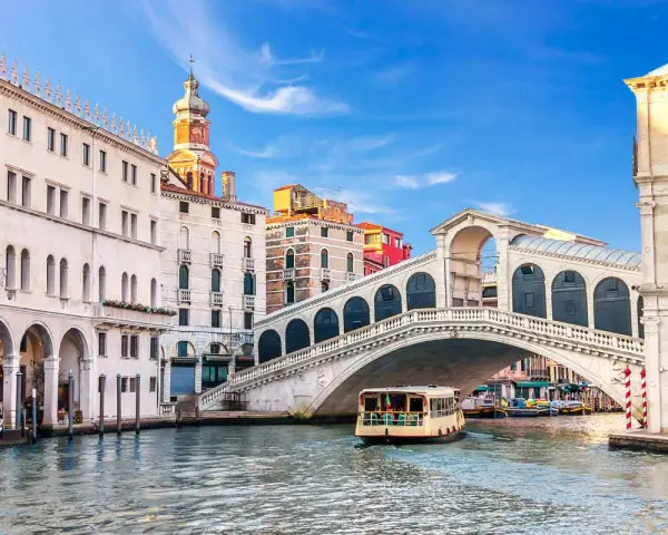 Venezia, il Canal Grande con il Ponte di Rialto e il Fondaco dei Tedeschi sullo sfondo. Una motonave naviga sull'acqua.