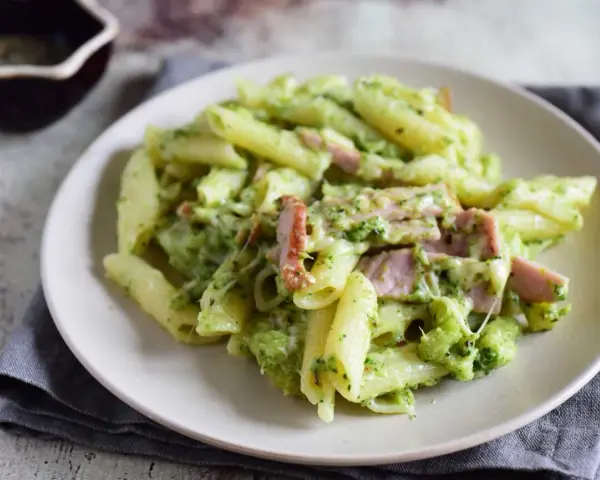 Penne z brokułami i kawałkami szynki w kremowym sosie śmietanowym, posypane serem. Pyszne danie, które zachwyci każdego.