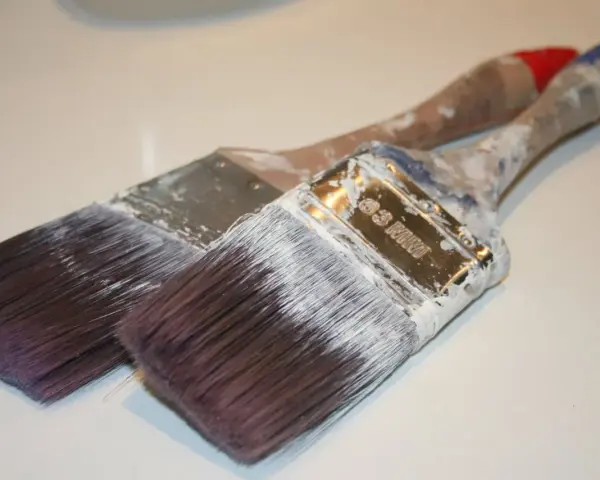 Deux pinceaux usagés, couverts de peinture blanche séchée. Que faire avec ce pinceau sec ?