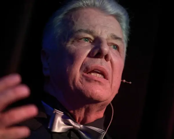 Emilian Kamiński, znany z wielu filmów, w eleganckim stroju z muszką, przemawia na scenie.