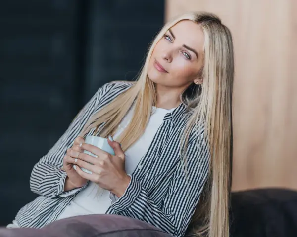 Blondynka z kubkiem w dłoniach, zamyślona, chce być sama.
