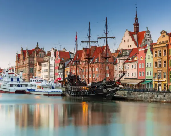 Gdański port z żaglowcem i kolorowymi kamienicami. To miejsce, co warto zwiedzić w Polsce, zachwyca historią i widokami.
