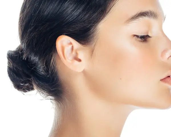 Profilo di donna con trucco leggero, evidenziato il contouring naso per un effetto scolpito. Pelle luminosa e capelli raccolti.