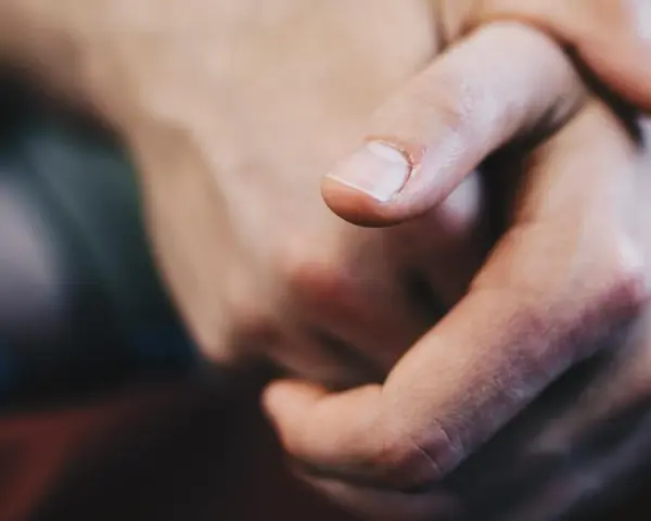 Dita intrecciate, un primo piano che evoca il senso di vibrazione interna e le sue cause, forse ansia o attesa.