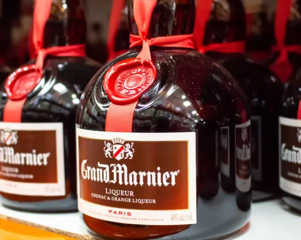 Butelki likieru Grand Marnier, idealnego do margarity. Czerwona wstążka i pieczęć dodają elegancji.