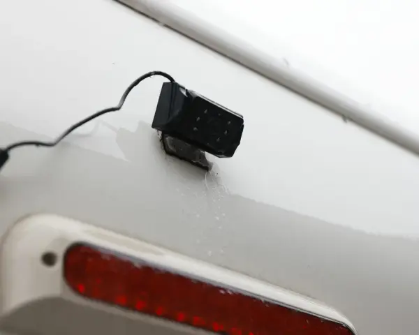 En liten svart backkamera monterad på en vit yta, redo att installera för bättre sikt bakåt.