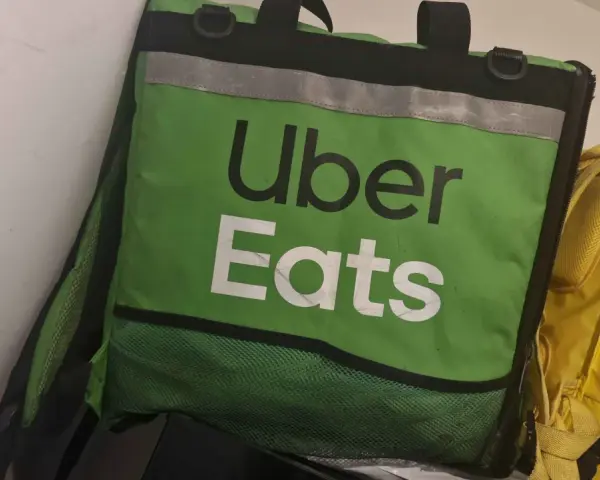 Zielona torba Uber Eats, obok żółtej torby Glovo. Taki widok może oznaczać potencjalne uber eats zarobki.