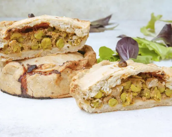 Panades mallorquinas cortadas, mostrando el relleno de guisantes y carne.