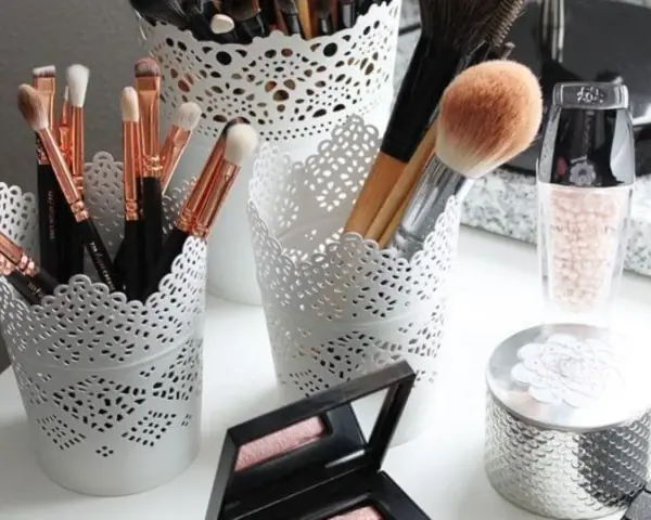 Des pinceaux de maquillage et des produits de beauté dans des pots ajourés. Une belle organisation pour le recyclage du maquillage.