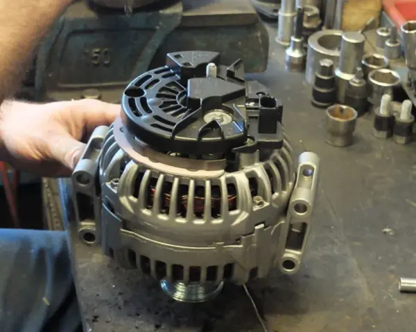 Warsztat samochodowy. Mechanik pracuje nad regeneracją alternatora. Sprawdź, jaka jest regeneracja alternatora cena.