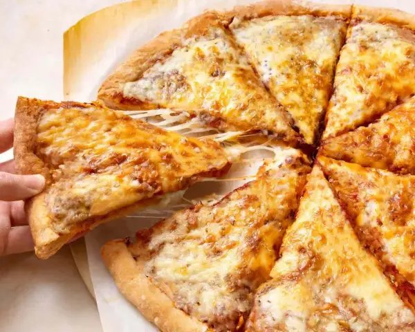 Pyszne, gorące ciasto na pizzę z ciągnącym się serem, które właśnie jest podnoszone.