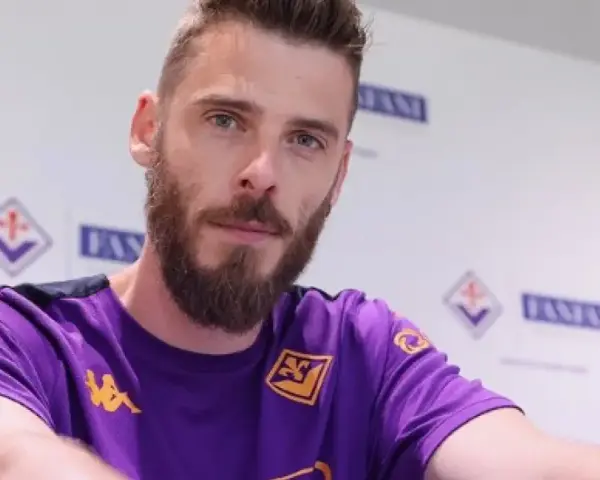 David de Gea, con barba y camiseta morada, posa ante un fondo con logos.