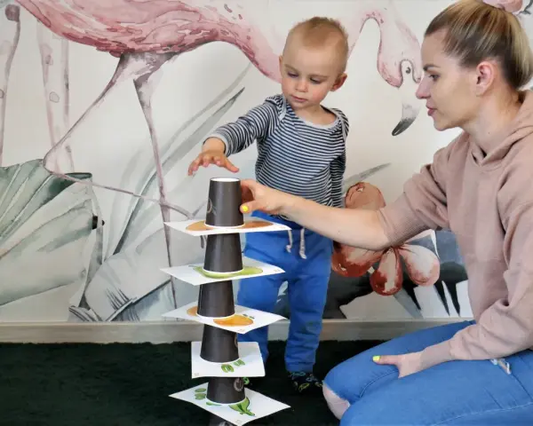 Mama i synek budują wieżę z kubeczków, ćwicząc naukę angielskiego dla 4 latka.