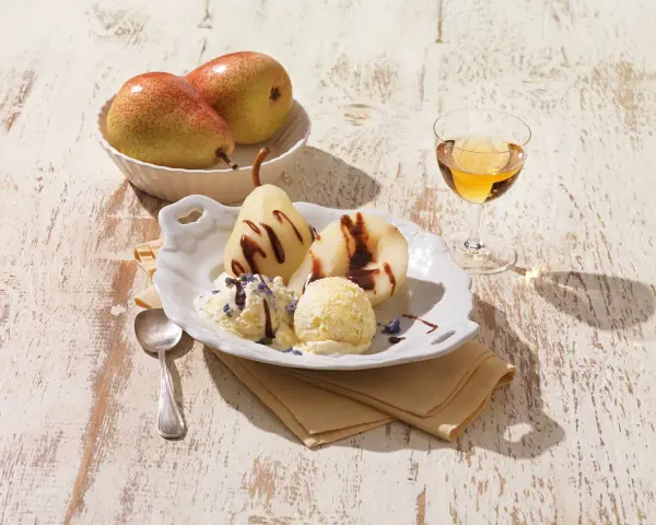 Gegarte Birnen mit Schokoladensauce und cremigem Vanilleeis, garniert mit Lavendelblüten. Ein köstliches Birnen Eis Dessert.