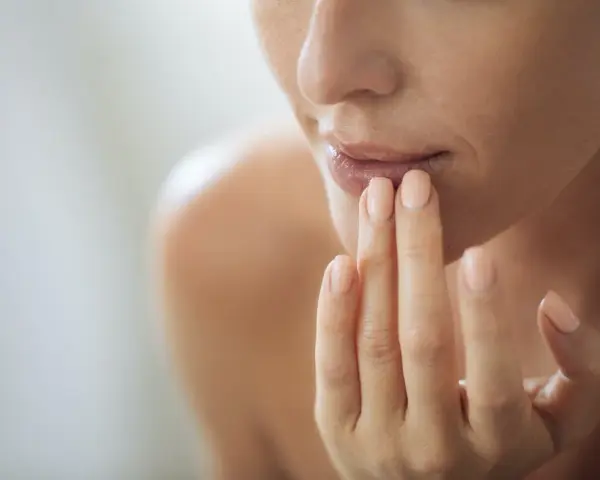 Nahaufnahme einer Frau, die sich mit den Fingern die Lippen berührt. Ein sanfter Blick auf natürliche Schönheit, vielleicht inspiriert von hausmittel gegen falten.
