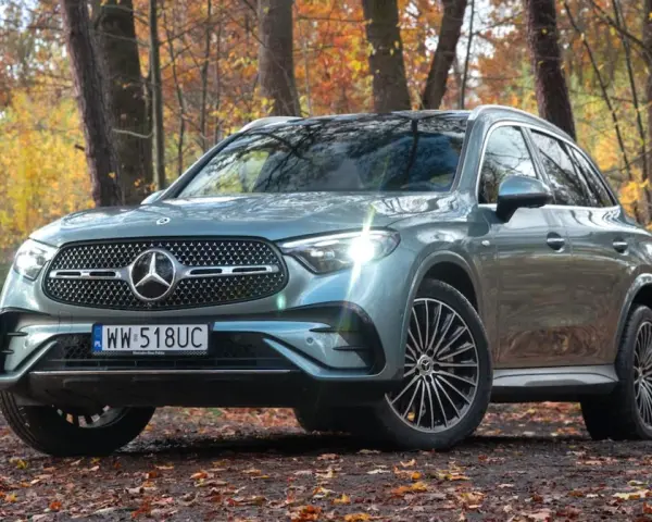 Elegancki Mercedes GLC 300 w jesiennym lesie, otoczony kolorowymi liśćmi.