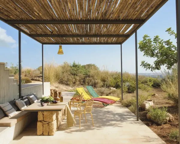 Porches sencillos y bonitos con mesa de piedra, asientos cómodos y tumbonas bajo un techo de madera.