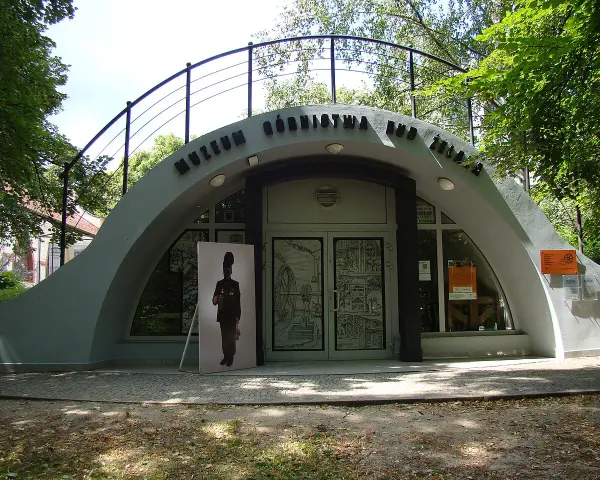 Wejście do Muzeum Górnictwa Rud Żelaza. Przed budynkiem stoi wielkoformatowy portret górnika.