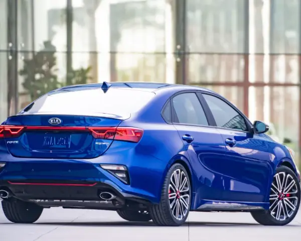 Niebieski sedan Kia Forte z widokiem z tyłu, z czerwonymi akcentami i sportowymi felgami.