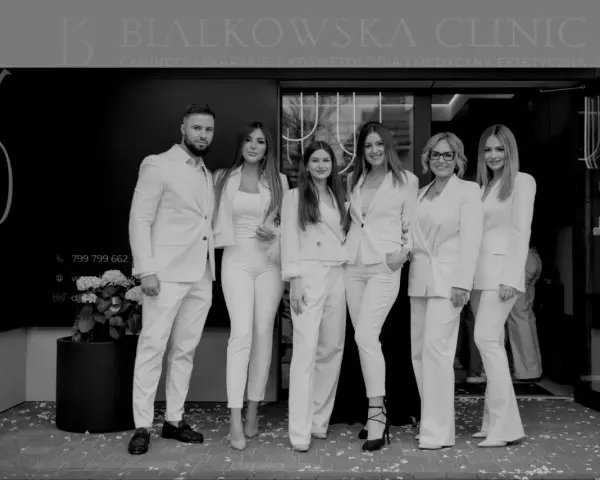 Sześć osób w białych strojach stoi przed kliniką.