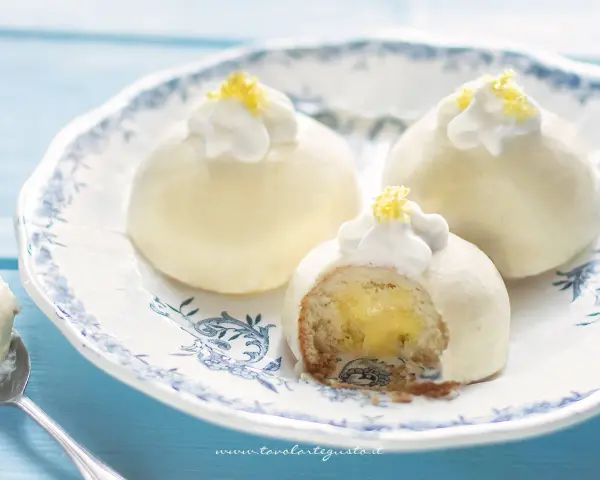 Deliziose tortine al limone, con un ripieno cremoso e una decorazione di panna e scorza di limone.