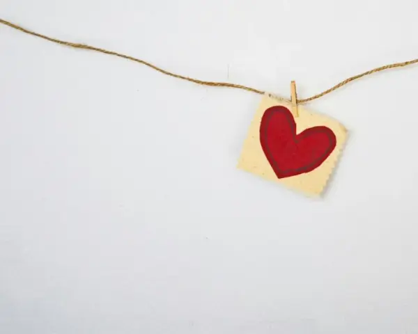 A red heart on a small fabric square, hung by a clothespin on a string. A simple symbol, asking: does God love everyone?