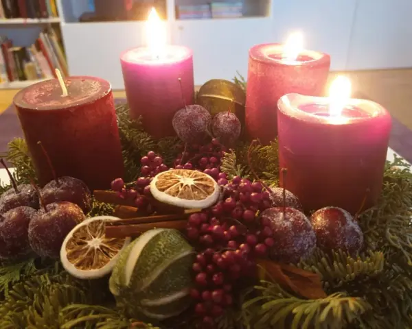 Adventskranz mit vier roten Kerzen, Tannenzweigen, Beeren, getrockneten Früchten und kleinen Äpfeln. Der 6. Sonntag nach Ostern ist noch weit, aber die Vorfreude auf Weihnachten ist spürbar.