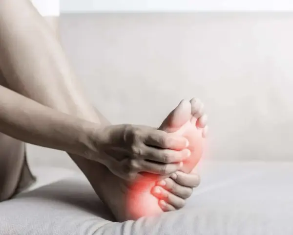 A person holds their foot, with red highlights indicating discomfort. This image evokes the feeling of needing natural foot detox.