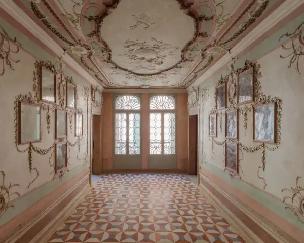 Corridoio decorato con stucchi dorati e specchi, soffitto affrescato e pavimento a rombi. Un assaggio dell'eleganza del Casino Venier.