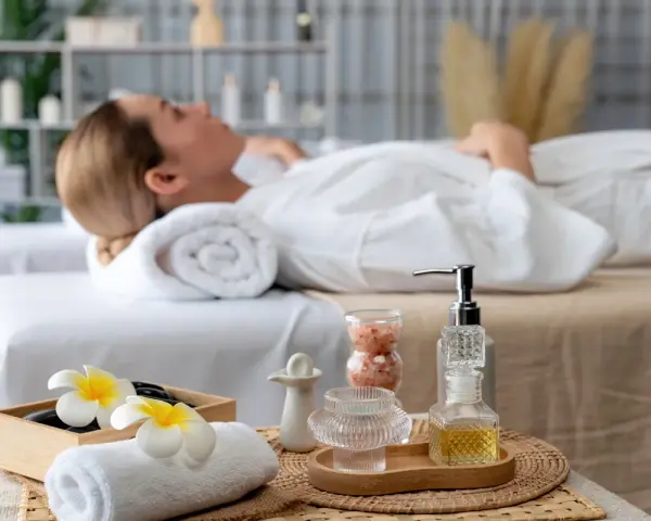 Relaks w jednym z hoteli spa Polska. Kobieta w białym szlafroku leży na łóżku, otoczona kosmetykami i kwiatami.