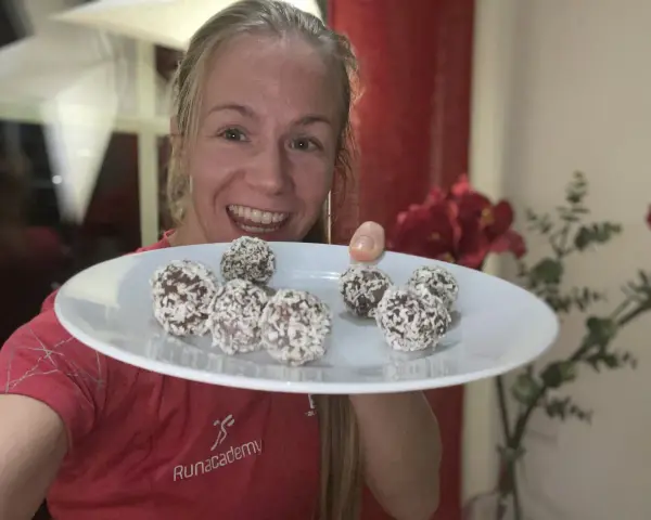 Glad kvinna visar upp en tallrik med hemgjorda chokladbollar, perfekta för ett snabbt och enkelt chokladbollar recept.