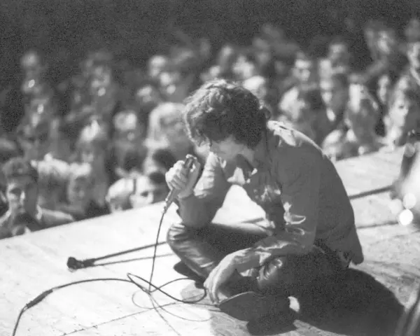 Jim Morrison z The Doors na scenie, wpatrzony w tłum. Jego "Paris Blues" rozbrzmiewa w sercach fanów.