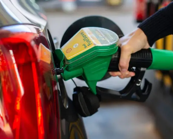 Tankstelle: Eine Hand betankt ein Auto mit dem grünen Zapfhahn. So behältst du im Blick, wie viel verbraucht dein Auto.