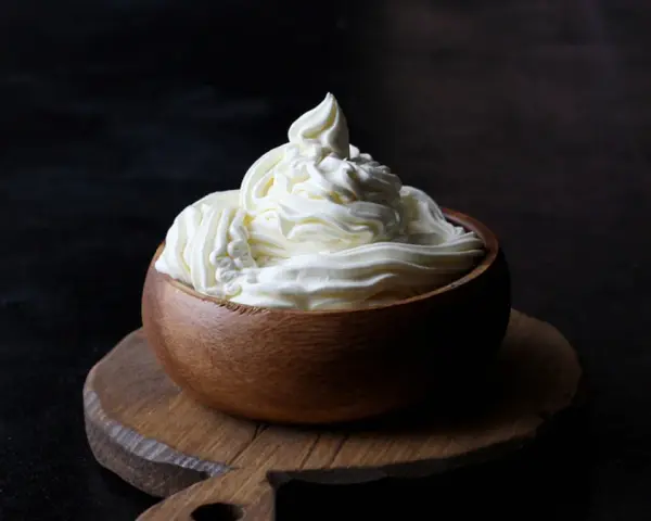 Kremowa masa w drewnianej miseczce, idealna do deserów. Mascarpone kontra serek homogenizowany – który wybierzesz?