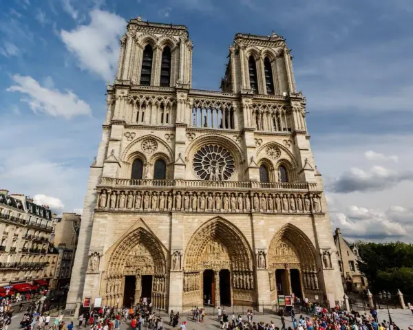 La fachada de Notre Dame, con sus torres gemelas y rosetón, se alza majestuosa. Hoy se puede visitar Notre Dame, un icono de París lleno de historia.