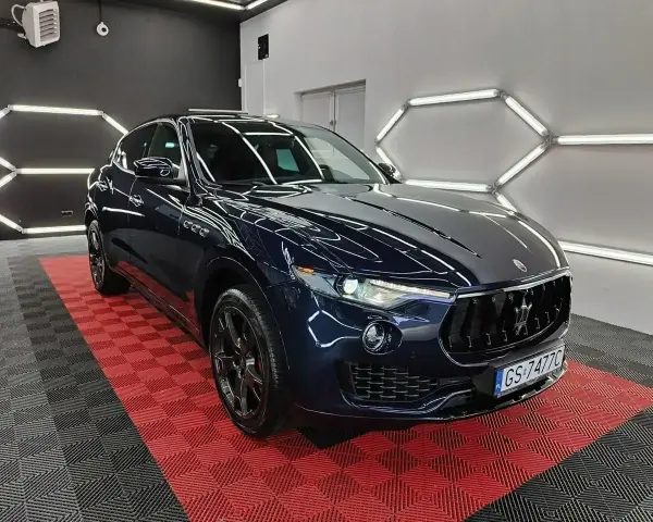 Lśniący, granatowy Maserati Levante na czerwono-czarnej podłodze. Sprawdź aktualną maserati levante cena i poczuj luksus.