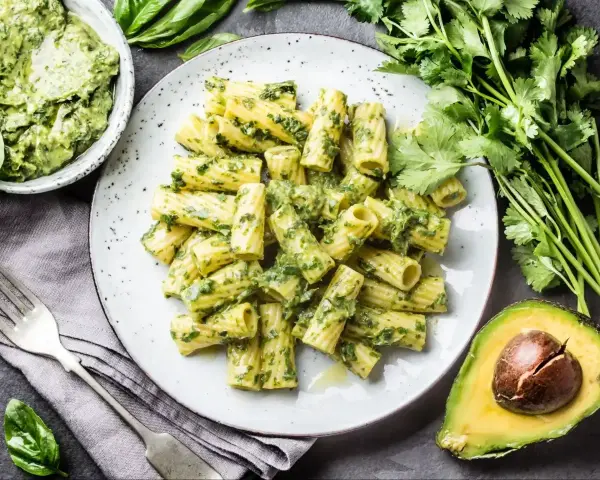 Pyszny makaron z pesto bazyliowym, podany z awokado i świeżymi ziołami. Idealny na lekki obiad.