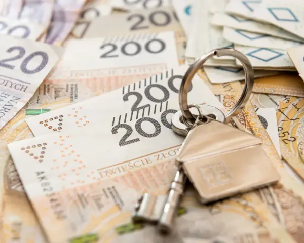 Klucze do domu na stosie polskich banknotów. Może to symbolizuje spłatę kredytu hipotecznego lub inwestycję, a może nawet windykację Santander.