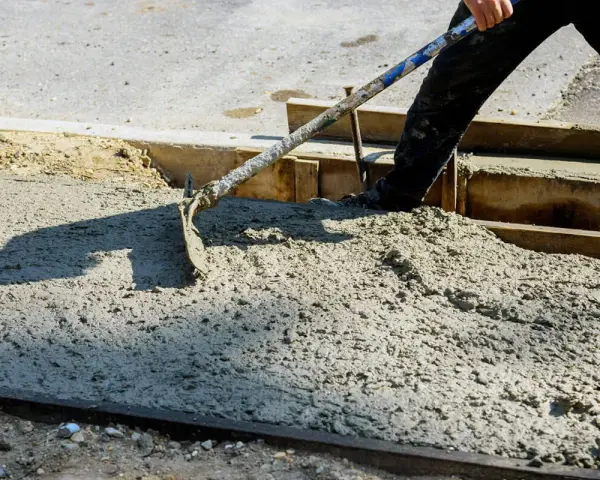 Pracownik rozprowadza świeży beton B25. Czas wiązania betonu zależy od wielu czynników.