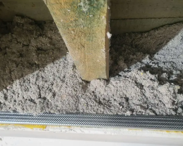 Izolacja z celulozy wypełnia przestrzeń między drewnianymi belkami stropowymi, tworząc warstwę termoizolacyjną.