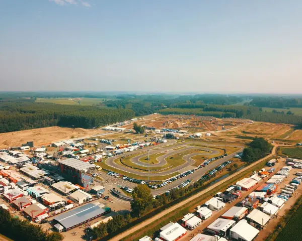 Vista aerea di un circuito **ottobiano motorsport** con paddock, tribune e pista da cross sullo sfondo, immerso nel verde.
