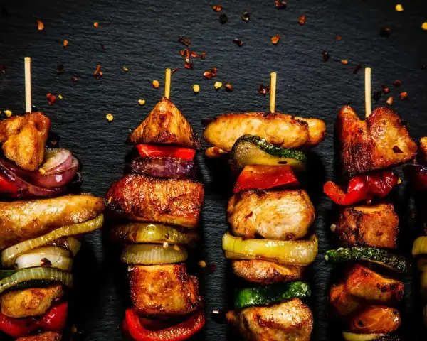 Spiedini di carne succulenti e colorati, alternati a cipolle, peperoni e zucchine, pronti per essere gustati.