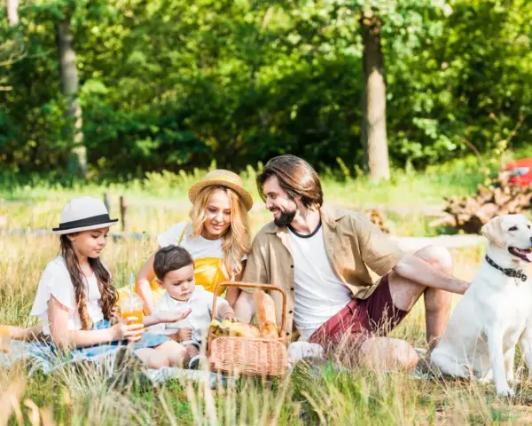 Familie genießt einen sonnigen **Picnic Berlin** im Grünen mit Hund.