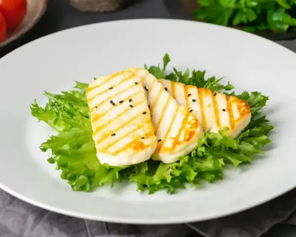 Grillowany ser halloumi na sałacie, posypany czarnuszką. Czy ser halloumi jest zdrowy? To pyszna przekąska.