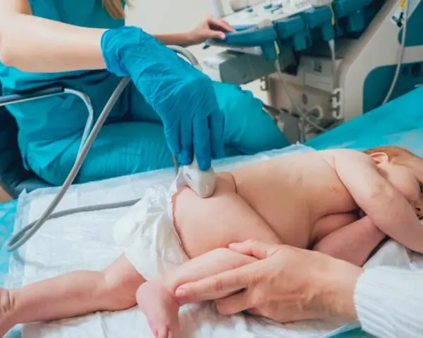 Lekarz wykonuje USG bioderka u niemowlaka. Badanie jest ważne dla prawidłowego rozwoju malucha.