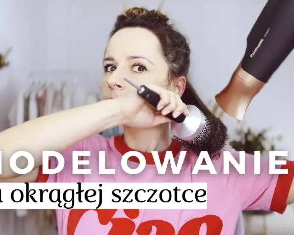 Kobieta modeluje włosy okrągłą szczotką i suszarką, tworząc efektowny blowout.